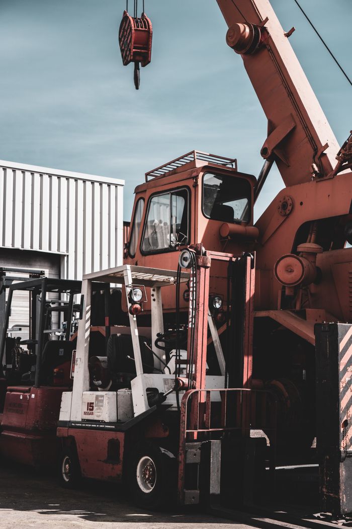 A crane and forklift in an outdoor German industrial zone under a clear sky.